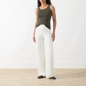 Model wearing Akris Punto olive cotton knit tank top with wide-leg cream trousers and black flat shoes.