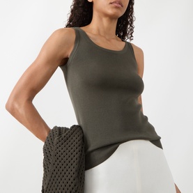 Model wearing Akris Punto olive cotton knit tank top, styled with white wide-leg trousers and a dark crochet cardigan