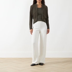 Model wearing Akris Punto olive cotton knit cardigan with white wide-leg trousers and black flats