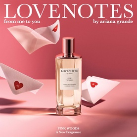 Ariana Grande Lovenotes Pink Woods EDP in glass bottle with gold cap, surrounded by paper heart envelopes on pink background