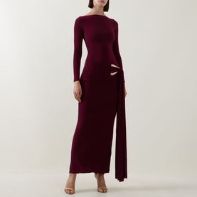 Model wearing Club London Burgundy maxi dress with long sleeves, cut-out waist detail, asymmetric drape skirt, styled with strappy heels.