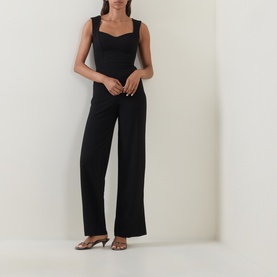 Model wearing Club London black sweetheart neckline jumpsuit with wide-leg trousers, styled with metallic kitten heel mules.