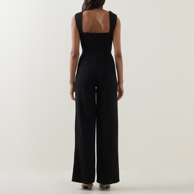 Model wearing Club London black wide-leg jumpsuit, back view, square neckline, sleeveless with structured straps