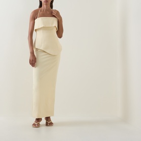 Model wearing cream strapless maxi dress with structured fold-over bodice, styled with gold flat sandals