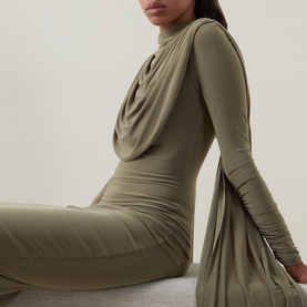 Model wearing khaki long-sleeve draped turtleneck bodycon midi dress with ruched detailing, seated pose