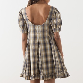 Model wearing Damson Madder dress in Cardamon Mix Check, showing low scoop back, puff sleeves, and ruffle hem detail.