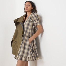 Model wearing Damson Madder Cardamon Mix Check cotton dress with puff sleeves and ruffle hem, styled with an olive utility vest.