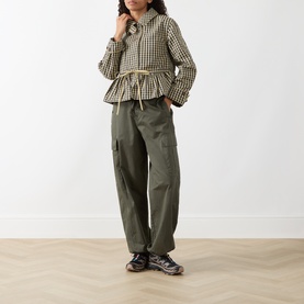 Model wearing Damson Madder Navy Gingham cropped jacket with drawstring waist, styled with khaki cargo trousers and dark trainers.