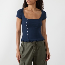 Model wearing Damson Madder navy ribbed top with square neckline, short sleeves, button front and frill hem, styled with khaki cargo trousers.