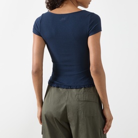 Model wearing Damson Madder navy ribbed short-sleeve top with frill hem detail, styled with olive cargo trousers. Back view.