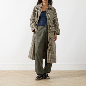 Model wearing Damson Madder navy top with check trench coat, olive cargo trousers and chunky trainers.
