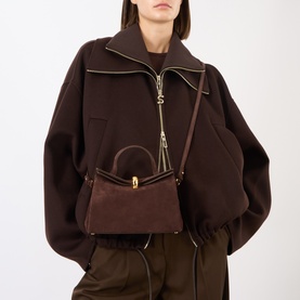 Model carrying Jacquemus Le Petit Valerie Shoulder Bag in medium brown suede with gold-tone half-donut closure and crossbody strap, styled with brown