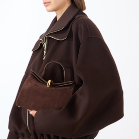 Model carrying Jacquemus Le Petit Valerie Shoulder Bag in medium brown suede with gold-tone half-donut closure and fold-over top detail, styled with