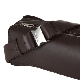Loewe Puzzle Featherlight Sling Bag in dark chestnut lambskin, close-up of silver-tone engraved logo plaque and zip closure detail.