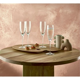 Luigi Bormioli Michelangelo Masterpiece Clear Flute Glasses, set of four, styled on a round wooden table with small bites and a ceramic sculpture.
