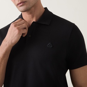 Model wearing Moose Knuckles black cotton polo shirt with tonal logo embroidery at chest and short sleeves, close-up detail shot