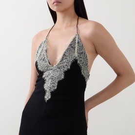 Model wearing Munthe Cielo Cape Dress in black with silver lace trim detachable cape and V-neckline, slim straps visible