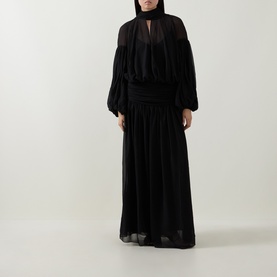Model wearing Munthe Solana Pussy-Bow Gown Dress in black, featuring puff sleeves, gathered waist, and pleated maxi skirt