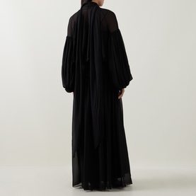 Model wearing Munthe Solana Pussy-Bow Gown Dress in black, rear view, showing puff sleeves, pussy-bow collar and pleated maxi skirt.