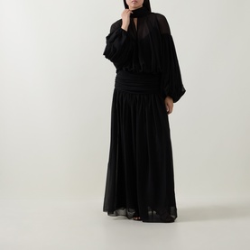 Model wearing Munthe Solana Pussy-Bow Gown Dress in black with puff sleeves, gathered waist, and pleated maxi skirt