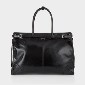 Prada black leather tote bag with top handles, buckle strap details, and silver-tone hardware on white background.