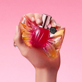 Viktor & Rolf Bonbon EDP held in hand, featuring a vibrant red and orange oversized bow-shaped bottle with rose gold cap