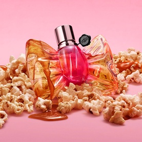 Viktor & Rolf Flowerbomb EDP in amber and pink sculptural bow bottle, surrounded by popcorn on a pink background