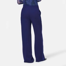 Model wearing Helen McAlinden Ink Blue wide-leg trousers, rear view, styled with a sheer floral top.