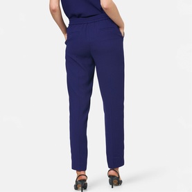 Model wearing Helen McAlinden ink blue tapered trousers with elasticated waist, shown from behind, styled with black heeled sandals.