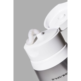 Anua cleanser in white pump bottle, close-up of flip-top dispenser nozzle with cream product visible
