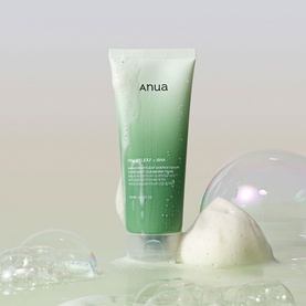 Anua cleanser in green tube shown with foamy lather and ice cubes on a light surface