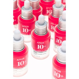Anua 10+ serum in pink dropper bottles with silver caps, multiple units displayed in a flat-lay arrangement