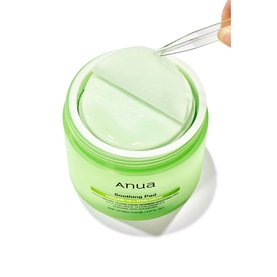 Anua Soothing Pad toner pads in green jar, lid open with tweezers lifting a single round pad