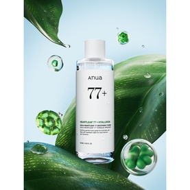 Anua Heartleaf 77% + Hyaluronic Acid toner bottle with green botanical leaves and water droplets on light blue background.