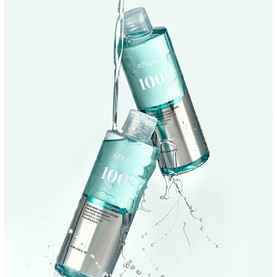 Anua toner in clear teal bottles with silver bases, shown mid-air with water splash, set of two