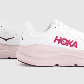 Hoka trainer in white and pink opal, featuring bold pink HOKA branding, chunky pink midsole and mesh upper, close-up detail shot.