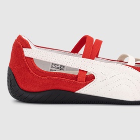 Red and white leather flat shoe with elasticated strap, perforated toe detail, and black rubber sole, close-up side view
