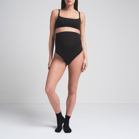 Model wearing Skims black bralette with matching black high-waist briefs and ankle socks