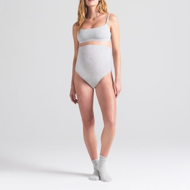 Model wearing Skims light heather grey bralette, styled with matching high-waist briefs and white ankle socks