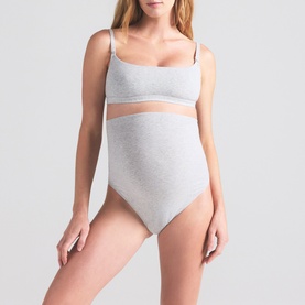 Model wearing Skims light heather grey bralette, styled with matching high-waist briefs in the same ribbed cotton fabric.
