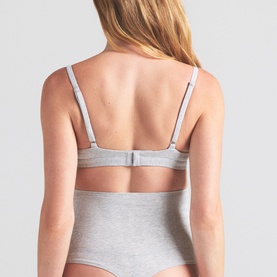 Model wearing Skims light heather grey bralette, back view showing adjustable straps and hook-and-eye closure, styled with matching briefs.