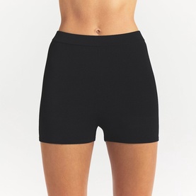 Model wearing Skims black shorts, fitted high-waist style with smooth fabric finish.