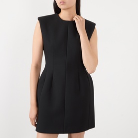 Model wearing The Frankie Shop black sleeveless mini dress with structured shoulders, pleated skirt detail and fitted silhouette.