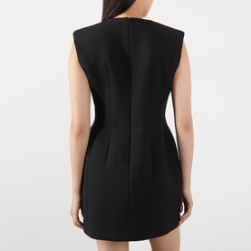Model wearing The Frankie Shop black sleeveless mini dress, rear view showing structured shoulders and fitted silhouette.