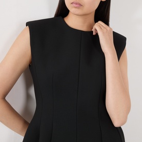 Model wearing The Frankie Shop black sleeveless dress with round neckline, structured shoulders, and front seam detailing.