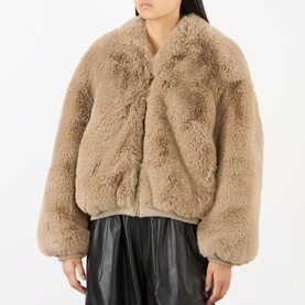 Model wearing The Frankie Shop light taupe faux fur bomber jacket with snap fastening, styled with black leather midi skirt.