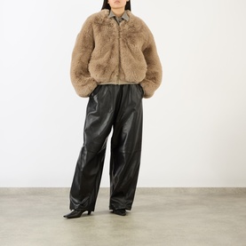 Model wearing The Frankie Shop light taupe faux fur jacket, styled with black leather wide-leg trousers and black heeled boots.