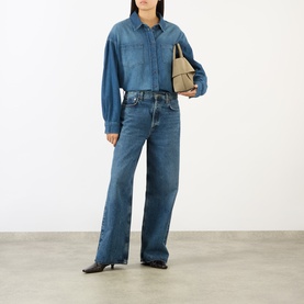 Model wearing The Frankie Shop Raw Wash denim shirt, styled with matching wide-leg jeans and carrying a small beige bag.