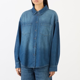 Model wearing The Frankie Shop raw wash denim shirt with chest pockets and snap buttons, styled with matching denim jeans