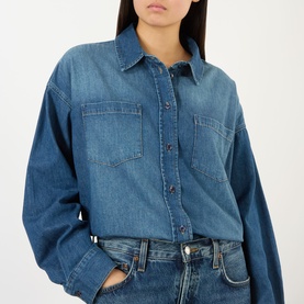 Model wearing The Frankie Shop raw wash denim shirt with chest patch pockets, styled with light blue denim jeans.